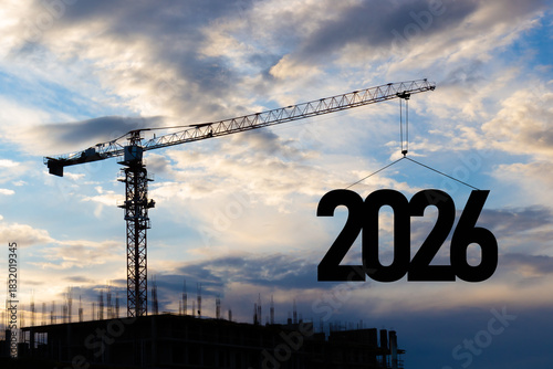 2026 New Year for planning and strategies concept background. Silhouette of a construction crane at a construction site raising the number 2026 year to blue sky. Ideas of development and investment