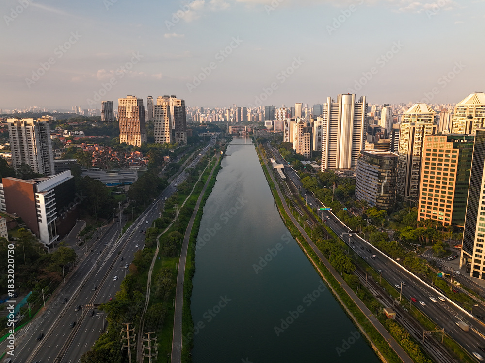 Fototapeta premium aerial view of Pinheiros river in Sao Paulo city with skyline in the distance during sunset