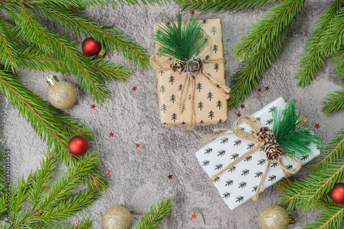 Christmas composition. Gift boxes, fir tree branches, red and gold decorations on grey background. High quality photo