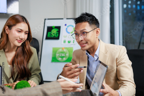 Asian business professionals collaborating in a corporate meeting, reviewing sustainability reports and environmental, social, governance strategies