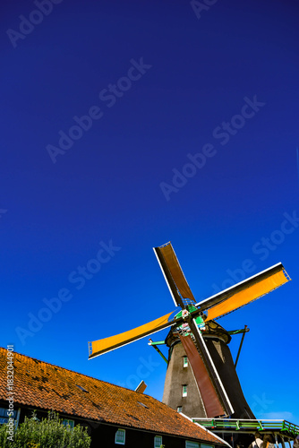 Vertical shot of a Dutch windmill offering ample copy space in the deep blue sky.