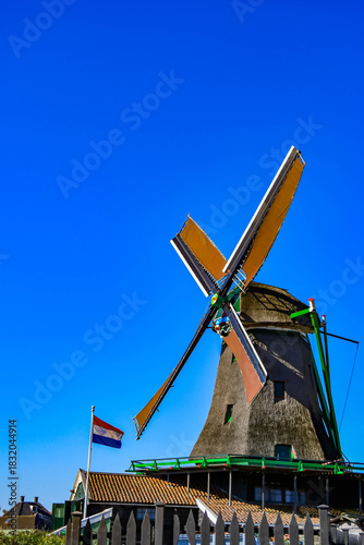 Symbol of the Netherlands: Traditional windmill and the Dutch flag waving in the wind