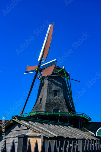 Traditional black wooden architecture and windmill at Zaanse Schans museum village.