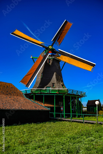 Traditional thatched windmill standing in a green field under a vibrant blue sky.