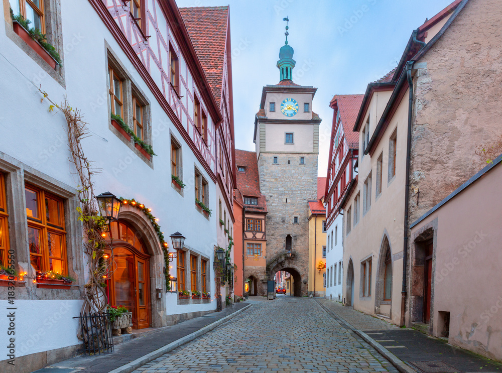 Fototapeta premium Roeder Arch and Markus Tower in Rothenburg ob der Tauber Germany at dawn with holiday lights