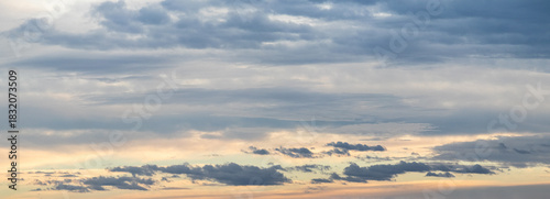 panoramic gray sky background with subtle pink-yellow hues on the horizon and multiple layers of clouds: from light transparent to dark and fluffy