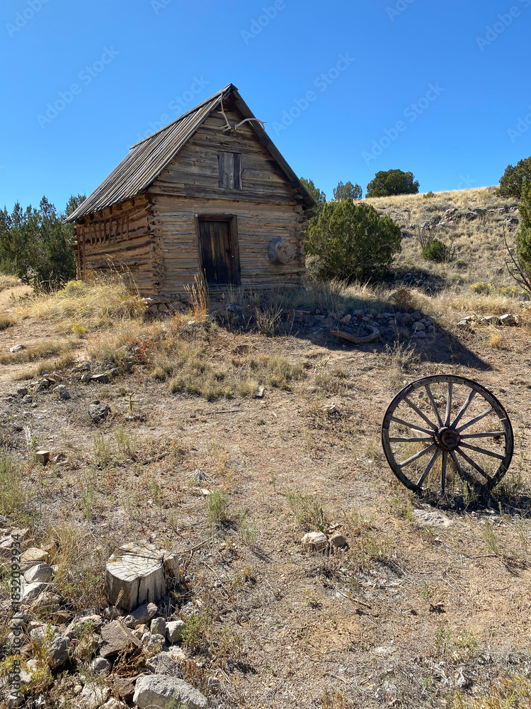 Obraz premium El Rancho de Las Golondrinas (The Ranch of the Swallows), historic rancho, now a living history museum near Santa Fe, New Mexico. Dispensa storage building and wagon wheel. 