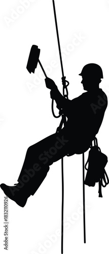 Silhouette of window washer rappelling down building