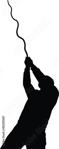 Silhouette of person pulling rope upward