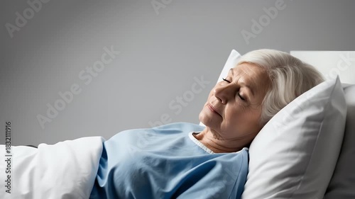 Elderly Woman Lying in Hospital Bed Wearing Blue Gown Against Gray Background