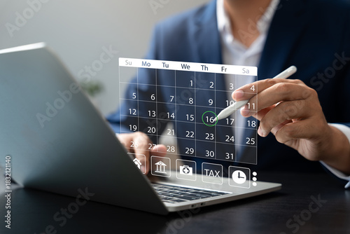 Businessman managing schedule with digital calendar interface on laptop using stylus pen, representing time management, event planning, productivity, and online appointments.
