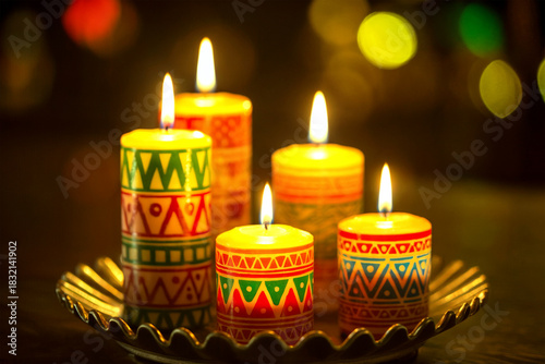 Colorful Patterned Candles Burning on Decorative Tray with Warm Bokeh Lights