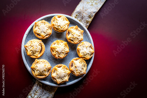 Christmas mince pies on a grey plate on a deep red background