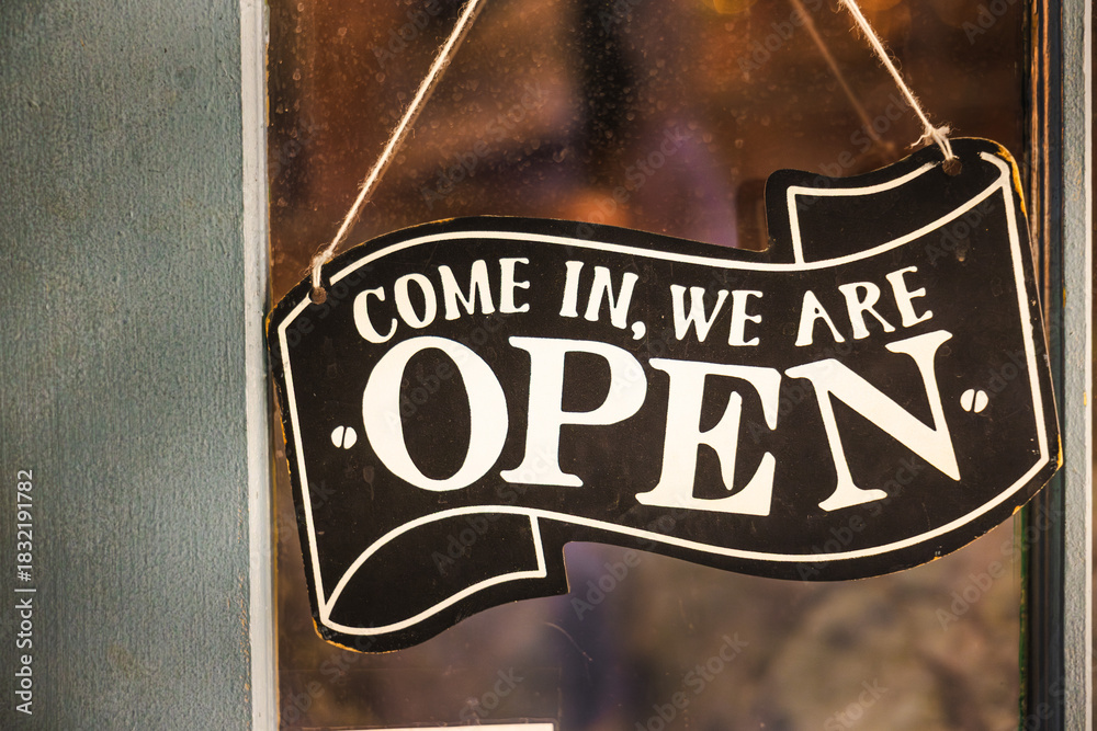 Fototapeta premium Vintage open sign hanging on a shop door with warm evening light in Toronto.