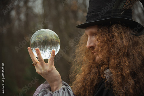 Mystical fortune teller holds crystal ball in a forest at dusk