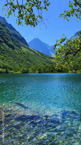 Turquoise water of the Baduk mountain lakes in a mountain valley in the mountains of the North Caucasus, on a sunny summer day. The blue sky and mountain peaks are reflected in the lake. 4К