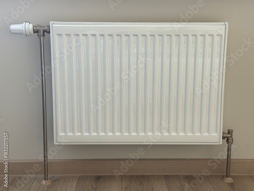 Wallpaper Mural White steel radiator on the background of a beige wall.
The heating level is regulated by a handle. Heating system of houses, apartments, offices and institutions. Torontodigital.ca