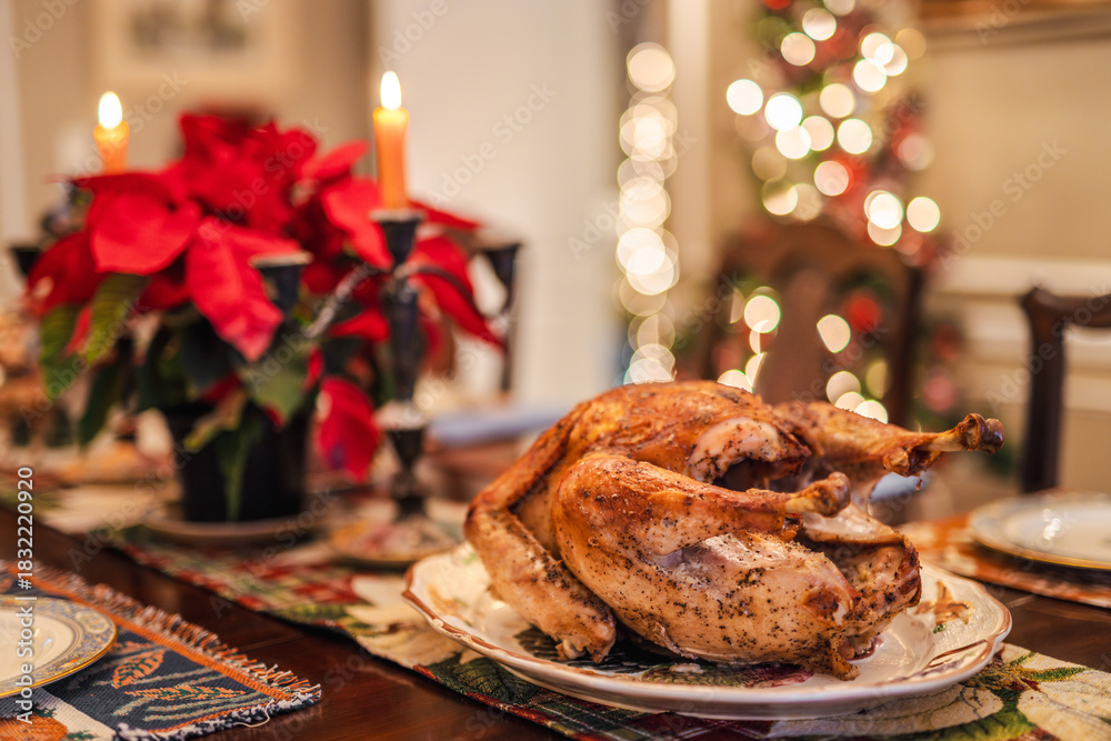 Fototapeta premium Holiday roasted turkey served on a festive Christmas table with candles, poinsettias, and warm bokeh lights, traditional for Christmas and Thanksgiving in the USA.