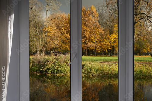 View from the window  on autumn landscape with a lake and bright yellow trees on the river bank.