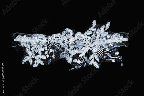 Women's wedding white lace garter on a black background.
