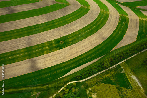 Aerial drone view of spring fields in South Moravia, Czech Republic, showing rolling green hills and soft patterns of cultivated farmland.