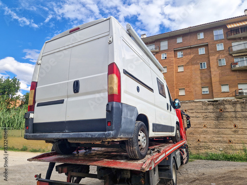 Rear view of tow truck carrying a broken down camper van