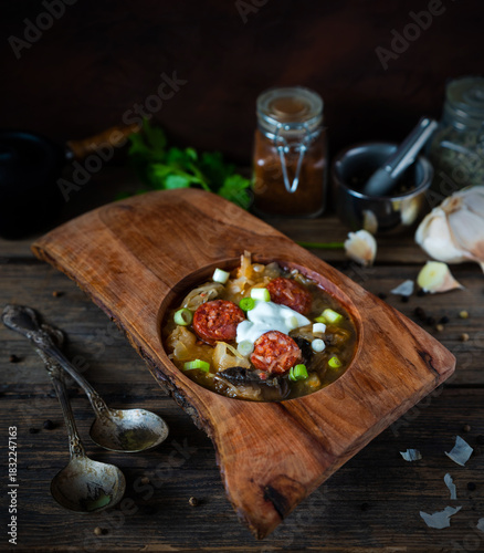Christmas cabbage soup kapustnica with mushrooms in a wooden bowl on a natural background with spices and garlic in the background.