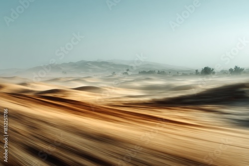 Fototapeta Naklejka Na Ścianę i Meble -  Sweeping desert landscape with sand dunes and distant mountains under a clear blue sky in motion blur