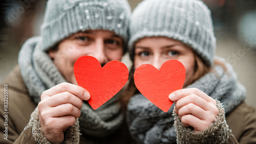 Couple heureux tenant chacun un coeur rouge