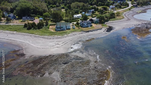 Wallpaper Mural Aerial view of a coastal village with pastel-colored houses and a fine sandy beach bordered by steep rocky reefs and waves of clear, sparkling water. Quebec, Canada. Torontodigital.ca