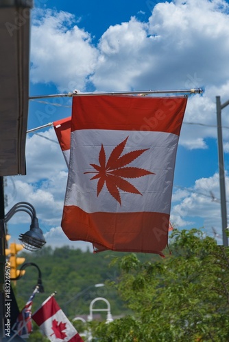 Canadian flag with marijuana leaf instead of maple leaf hanging from building.