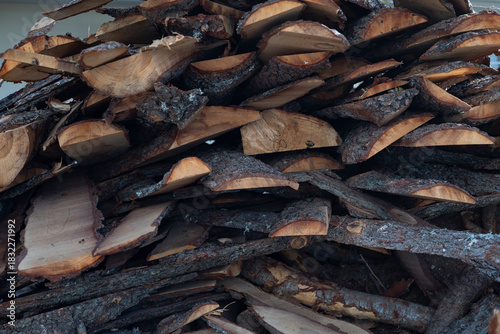 Close-up of stacked firewood made of natural wood. Visible wood cuts, bark, and layered textures emphasize the organic structure of the material.