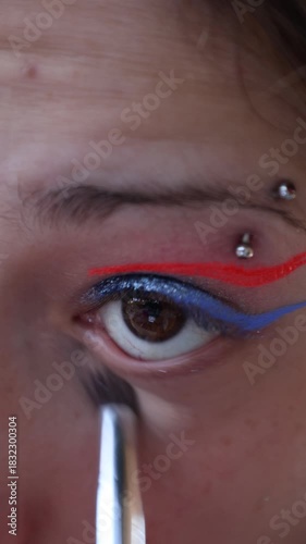 a Caucasian girl applying make-up to her lower eyelid with a brush