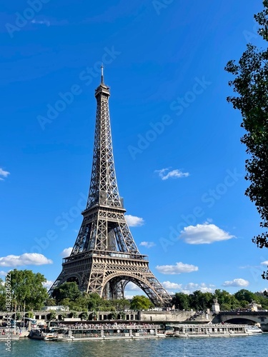 Eiffel Tower and Seine River cruise boats under blue summer sky in Paris
