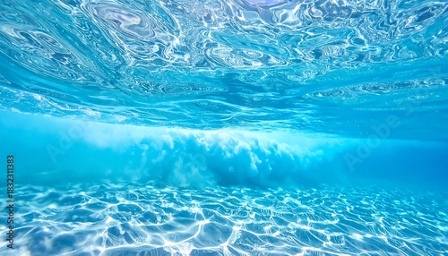 Fototapeta Naklejka Na Ścianę i Meble -  Underwater shot with sunlit sandy bottom and shimmering surface, showing a blurred transition of clear water and light