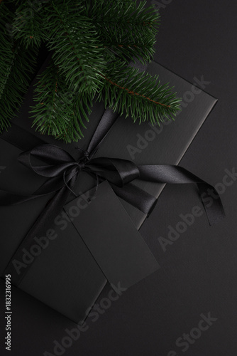 Black Christmas Gift Box with Satin Ribbon and Black Blanck Label on Dark Holiday Background