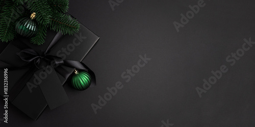 Black Christmas Gift Box with Satin Ribbon and Green Ornaments on Dark Holiday Background