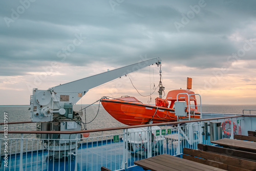 Orange rescue boat on a ferry deck during sunset sailing