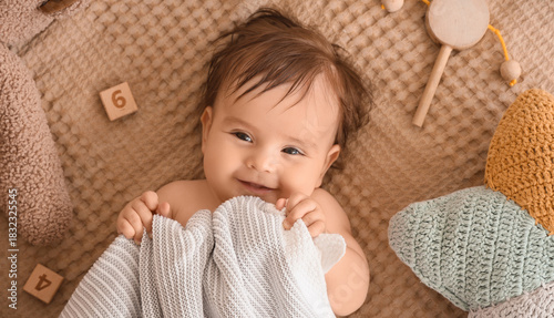 Cute little baby with plaid and toys lying on bed, top view