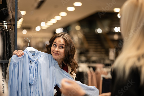 Woman making funny face deciding on buying blouse