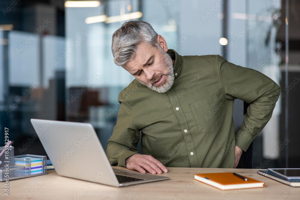 Ταπετσαρία Mature man in an office slumped at his laptop, wincing and rubbing his lower bac