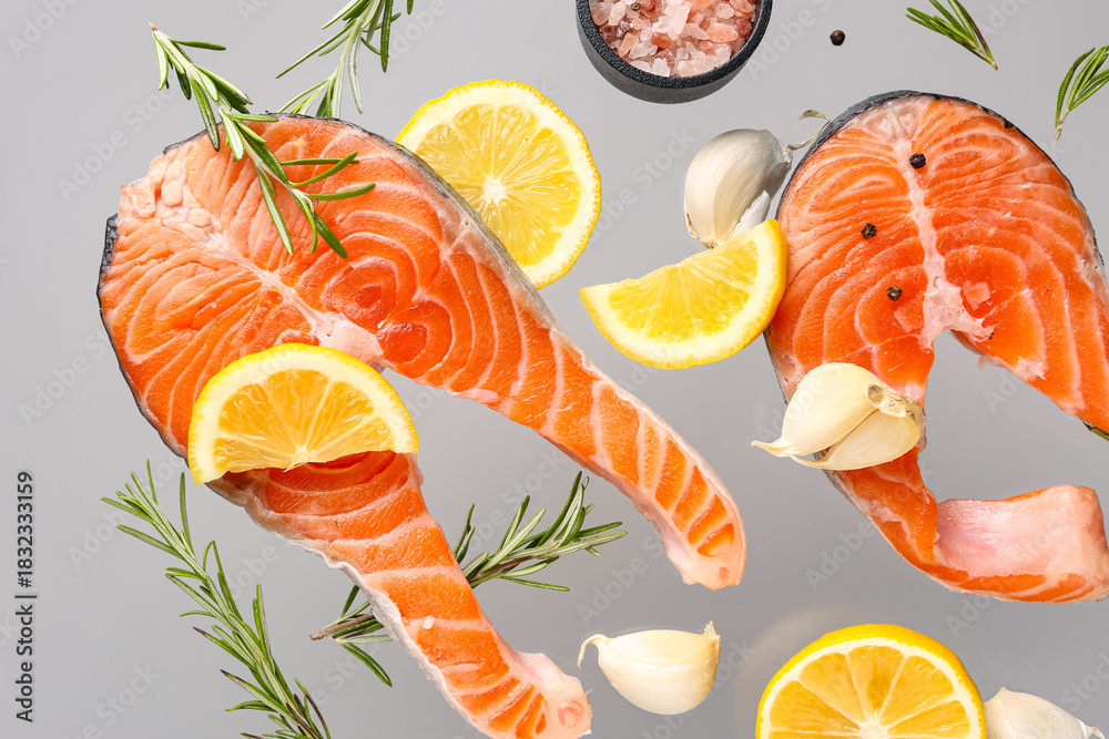 Fototapeta premium Flying raw salmon steaks and different spices on grey background