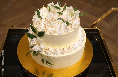 Wedding cake, a cream cake decorated with cream and flowers on a gold tray.