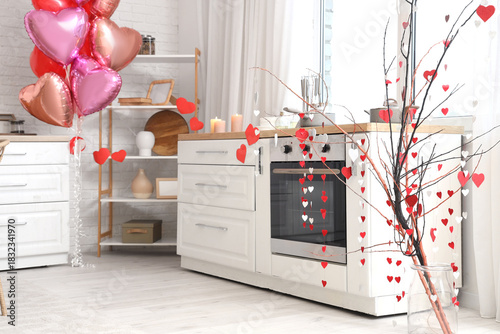 Tree branches with paper hearts garland in festive kitchen. Valentine's Day c...