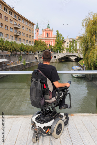Man tourist with a disability enjoys Europe Ljubljana scenery from the Ljubljanica bridge