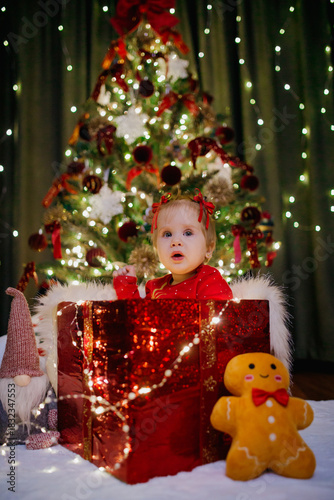 Little girl sitting in a gift box at Christmas day