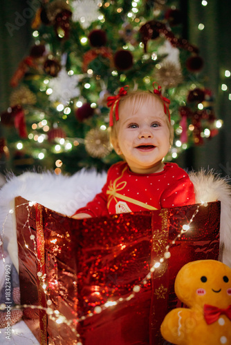 Little girl sitting in a gift box at Christmas day