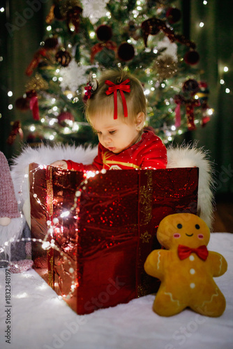 Little girl sitting in a gift box at Christmas day