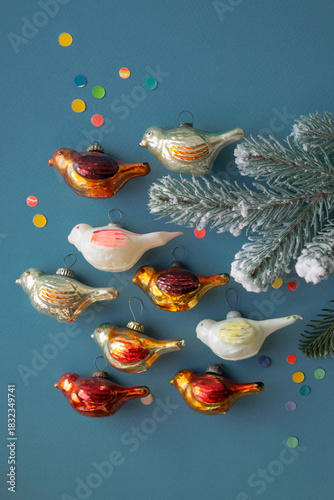 Old vintage Soviet Christmas ornaments birds with tree branch, top view on blue background, selective focus