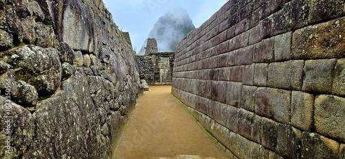 Interior passageway within the ancient Inca city of Machu Picchu in Peru - Pathway with Huyana Picchu in the background covered by clouds